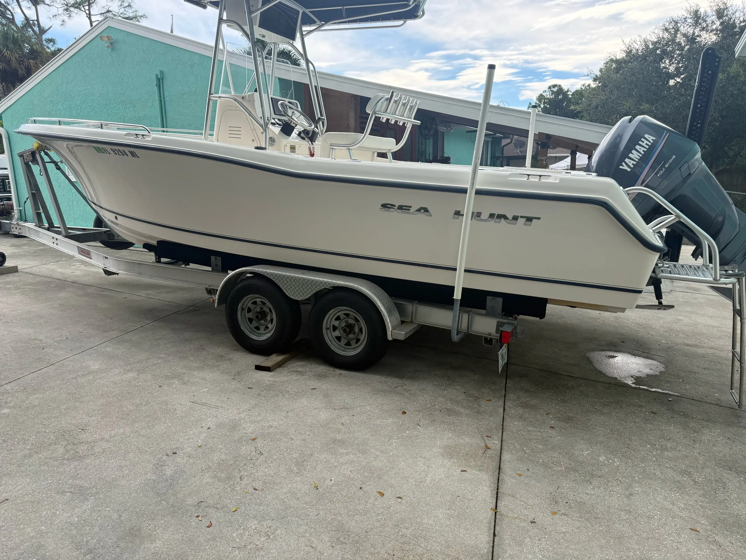 Center console boat on a trailer in a Naples driveway before detailing